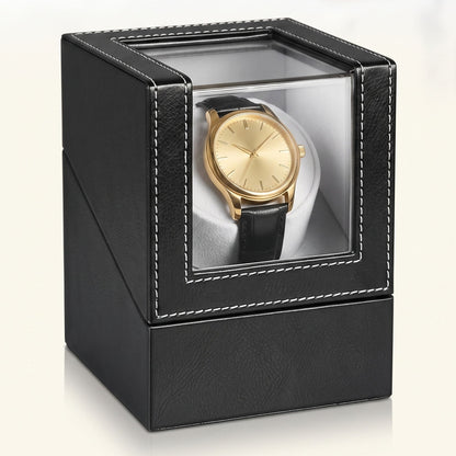 Remontoir de montre L'Écrin en similicuir noir, couvercle fermé et hublot vitré, sur fond clair