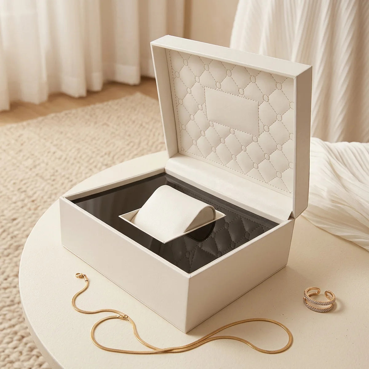 Boîte à montre Le Matelassé, coque ivoire et intérieur matelassé une table à côté d'un collier et d'un bracelet