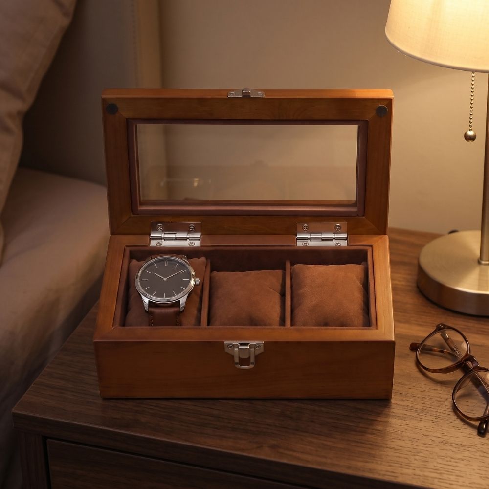 Boîte à montre en bois Le Comptoir III ouverte sur une table de chevet, une montre posée dans le premier des trois emplacements