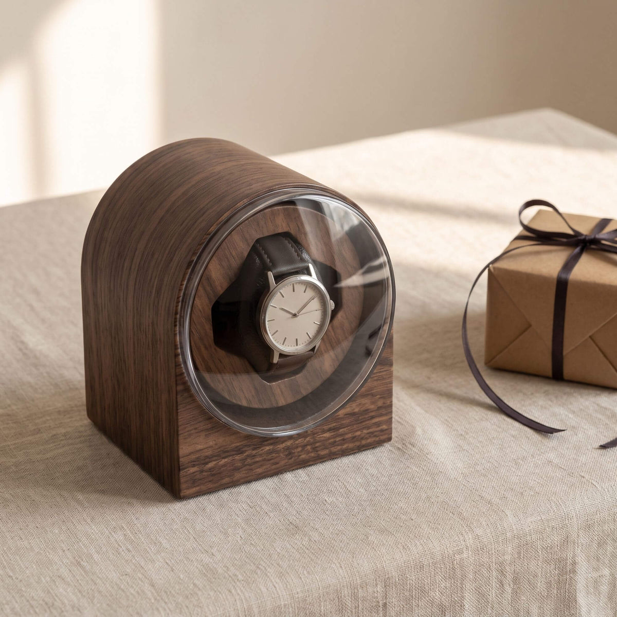 L'Arche sur une nappe en lin à côté d'un paquet cadeau en papier kraft noué d'un ruban