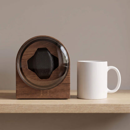 Taille du remontoir L'Arche comparée à un mug en céramique posé à côté sur une étagère en chêne
