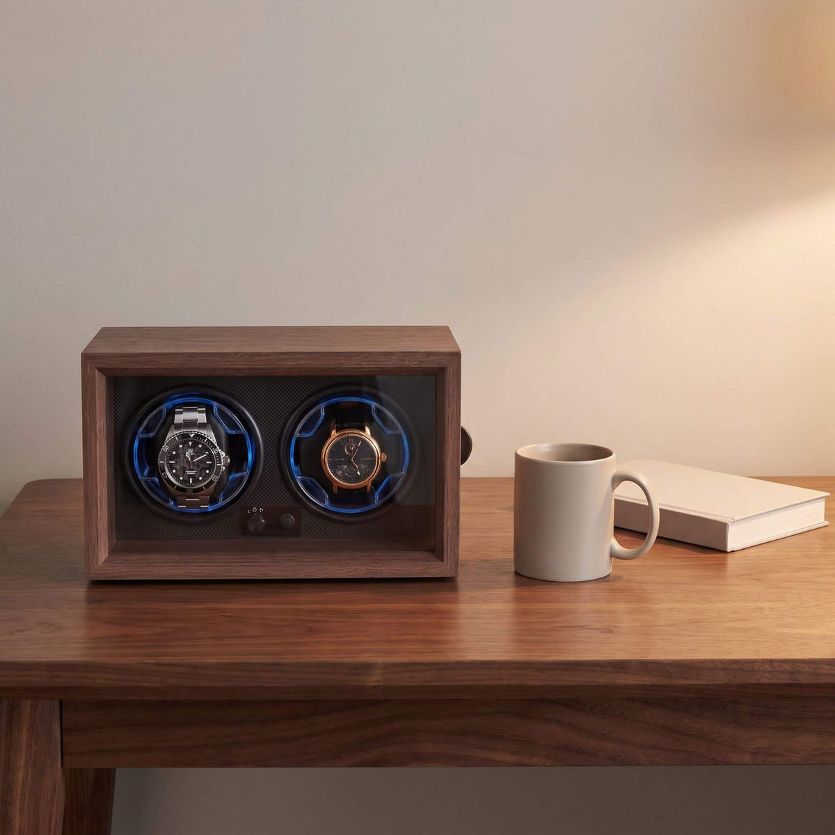 Remontoir deux montres de 24,5 cm de large sur un bureau, à côté d'une tasse et d'un livre