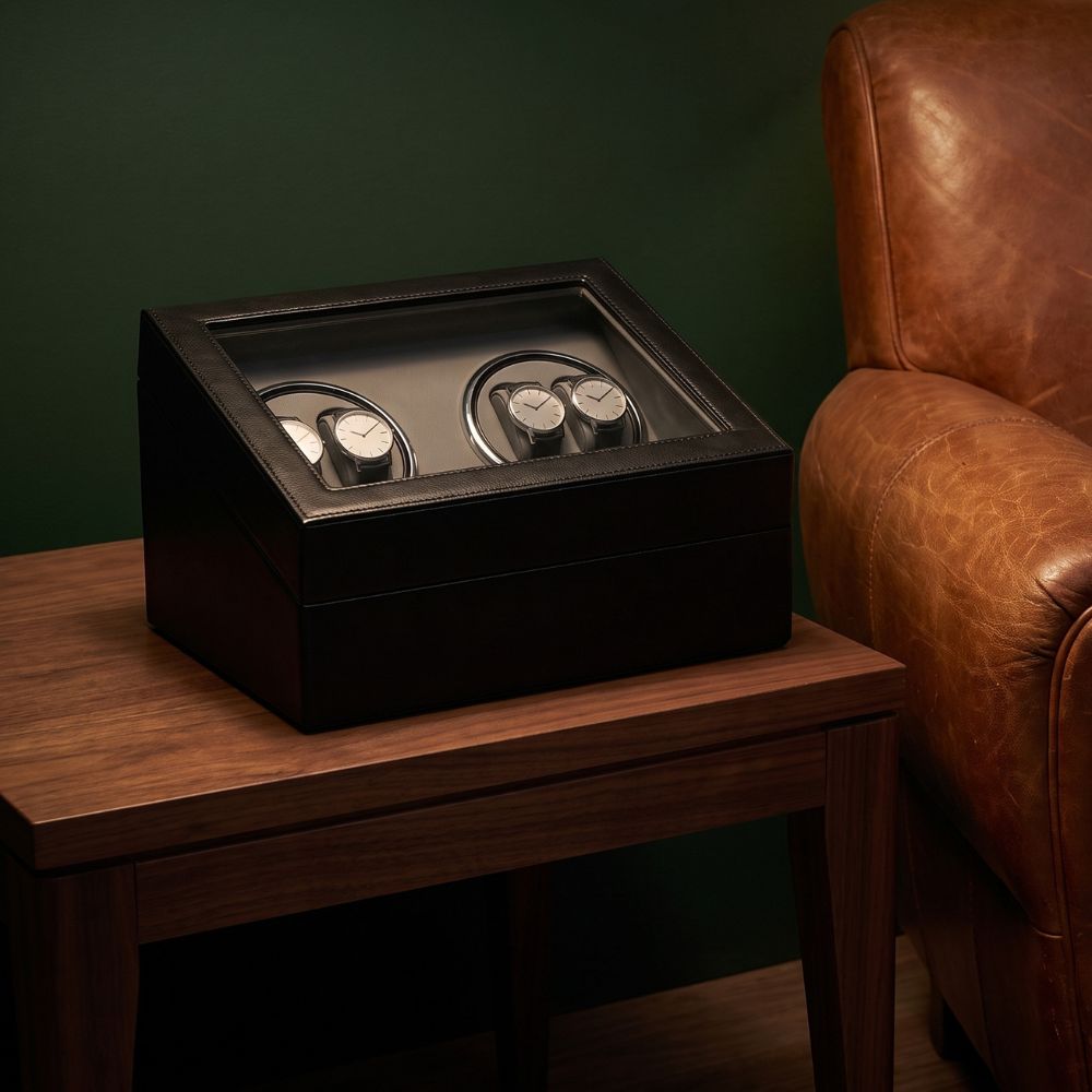 Coffret remontoir 4 montres posé sur une console en noyer près d'un fauteuil